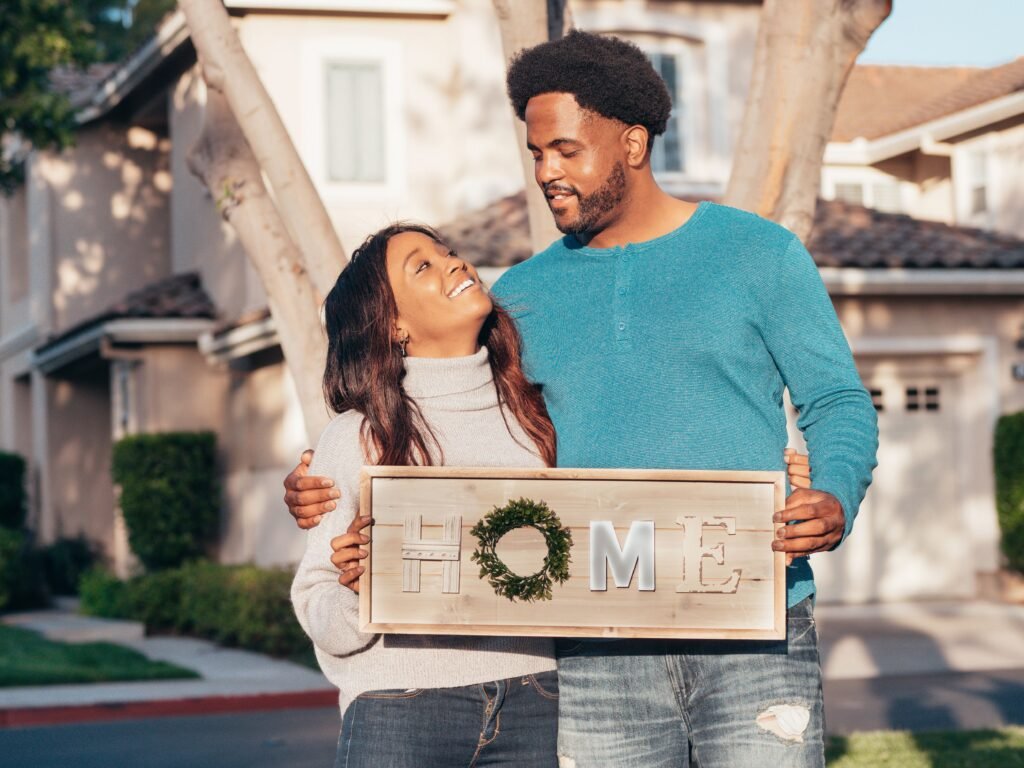 Testimonial of first‑time home buyers holding a sign celebrating their new home